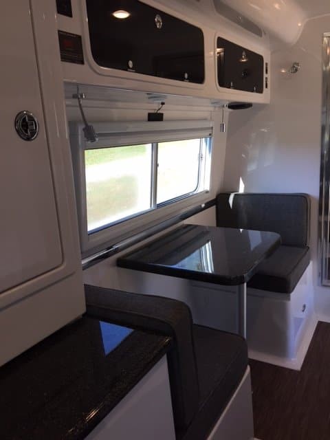 Dining room in an RV. Table is black and the seat cushions are dark gray.