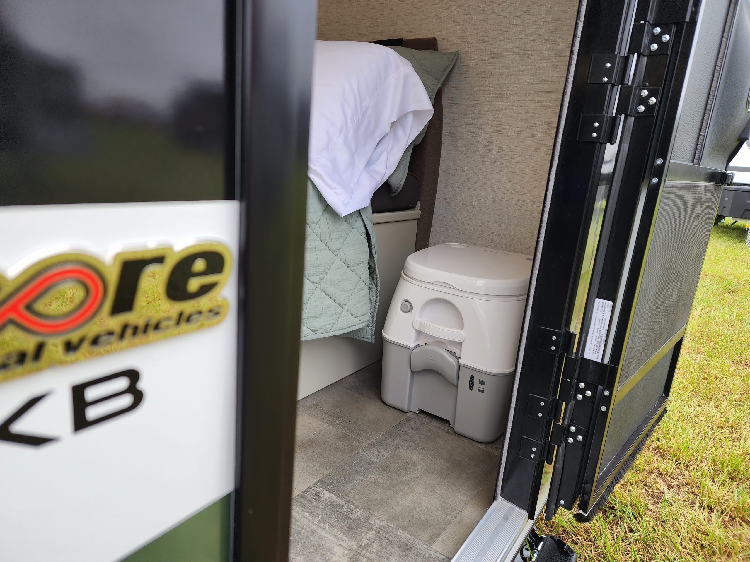 Dinette area converted into a bed in the Encore RV VENŪ 1500 lb travel trailer, showing the sleeping configuration.