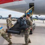 U.S. Air Force personnel load luggage onto an American Airlines plane at Ramstein Air Base during Operation Allies Refuge, showcasing the role of Civil Reserve Air Fleet Aircraft in passenger movement.