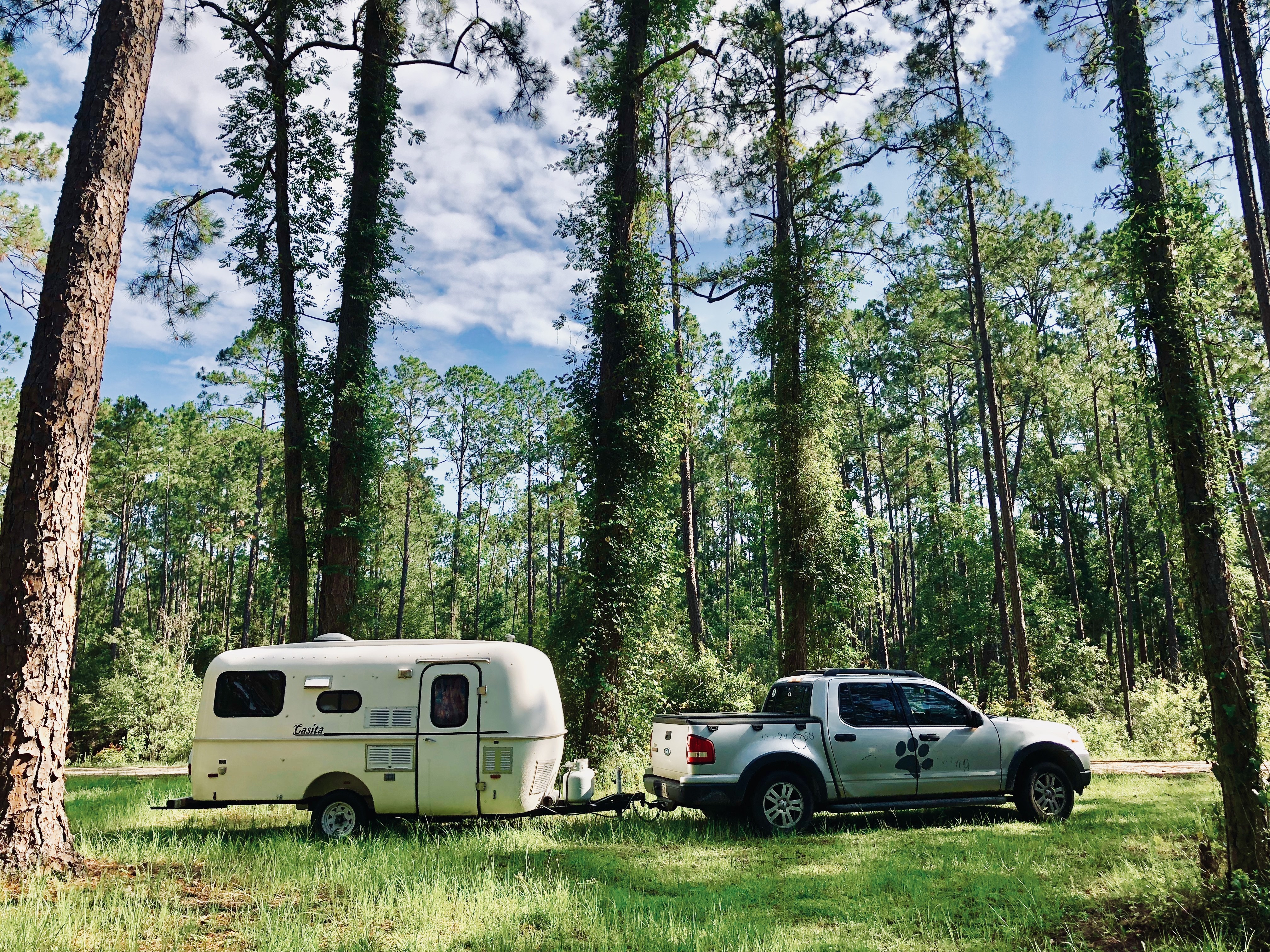 A woman standing in front of her Casita travel trailer in a scenic outdoor location.