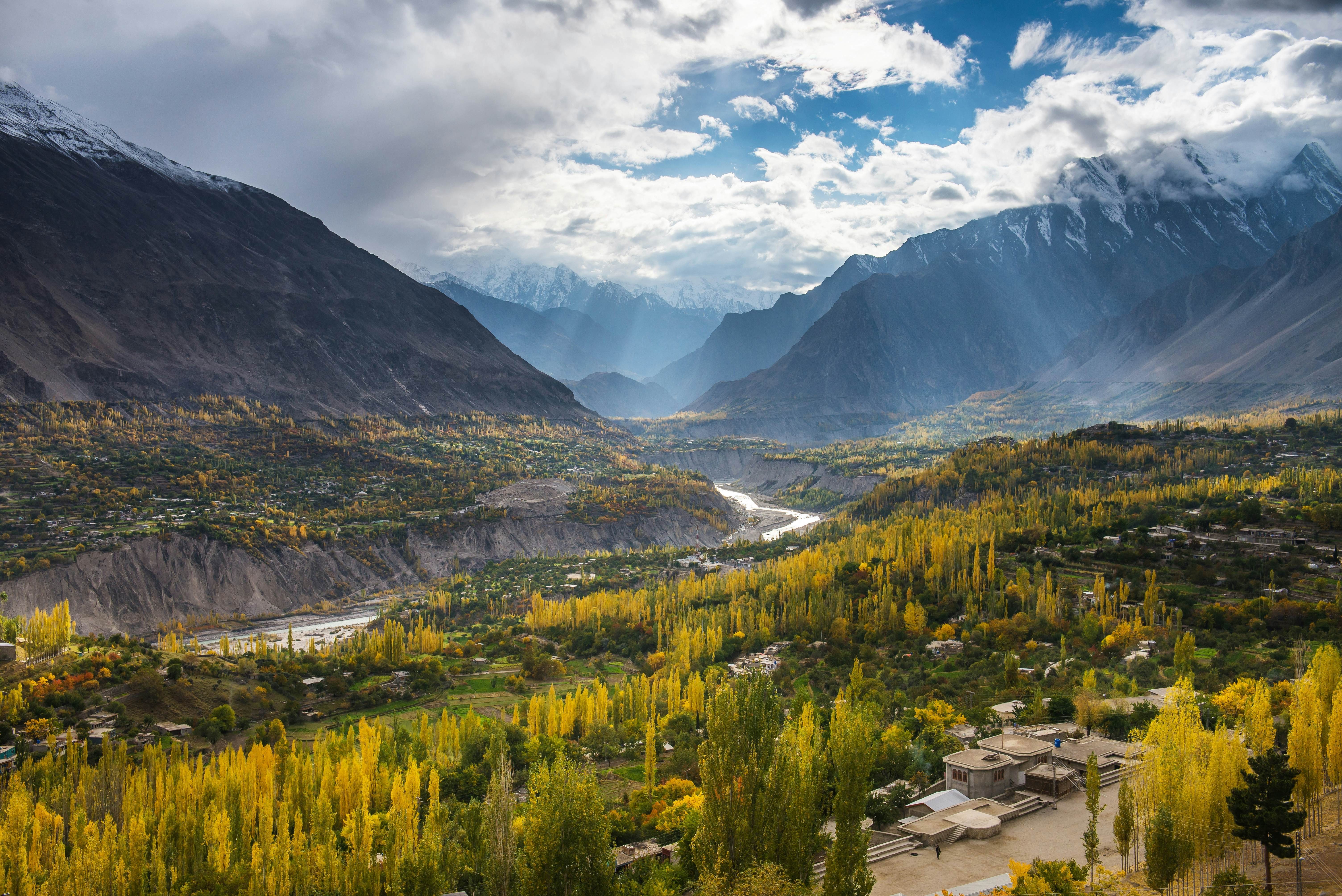 Hunza Valley in Northern Pakistan reveals dramatic mountain scenery, with glacial rivers carving through valleys in vibrant autumn colors