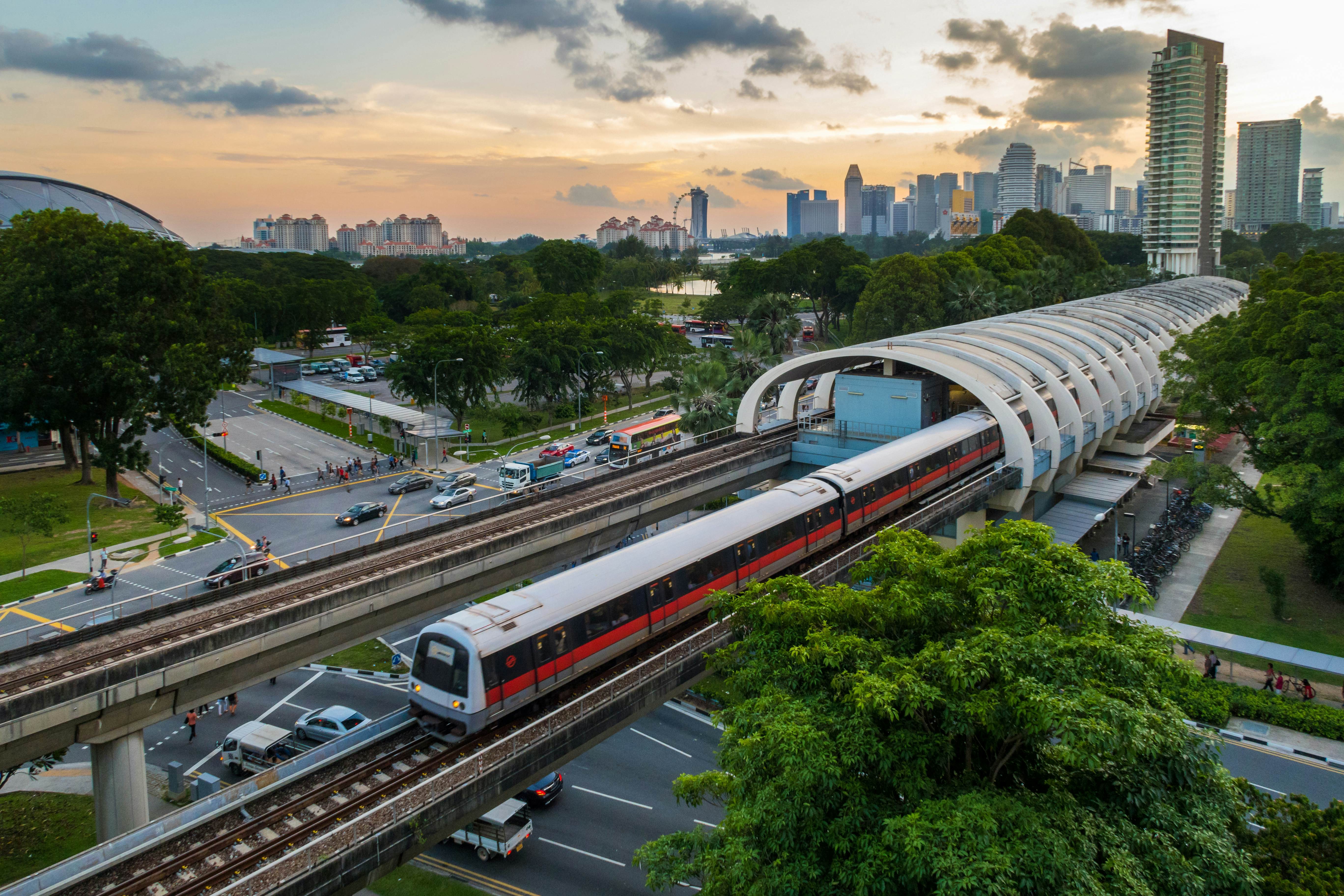 A modern MRT train arriving at a station in Singapore with skyscrapers in the background