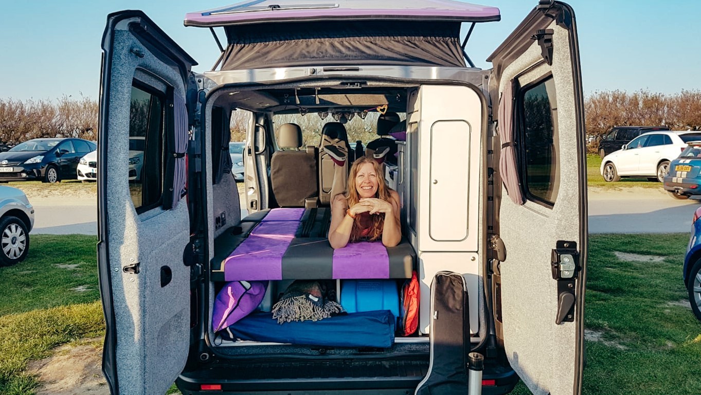 woman laying in the back of her camper van with bed pulled out