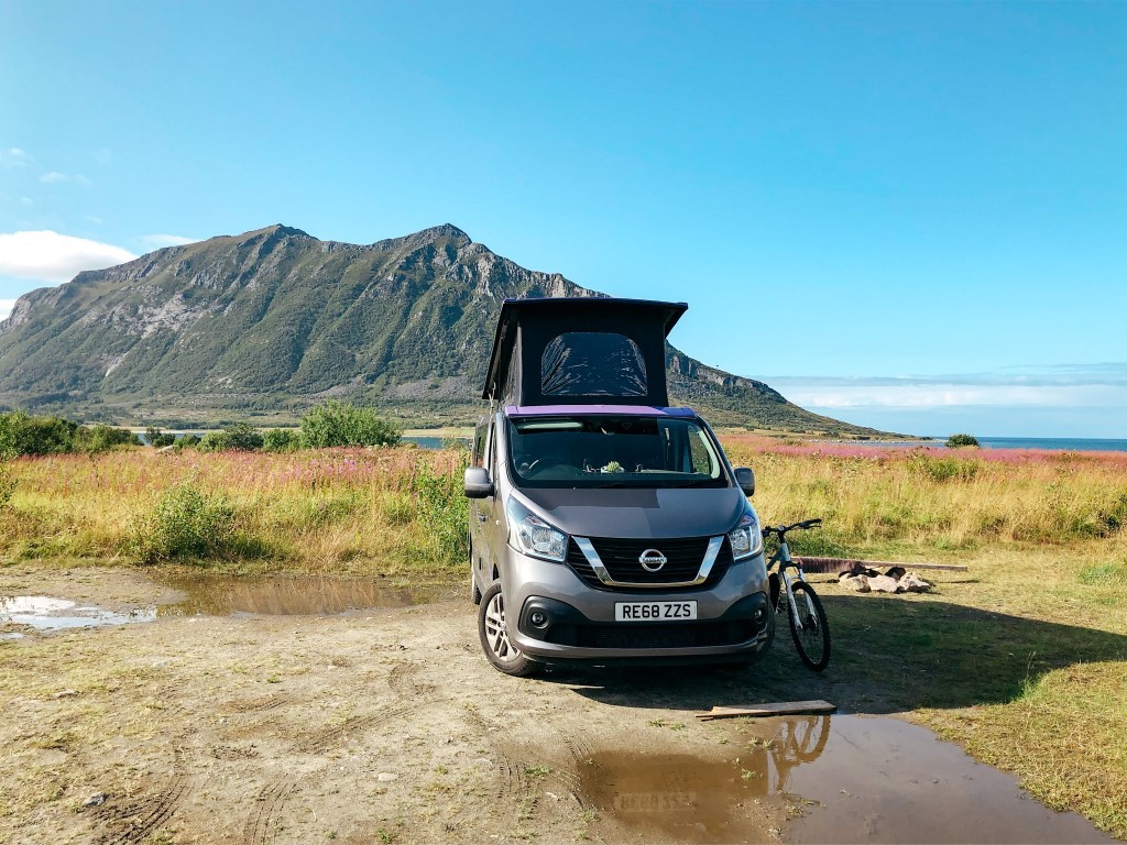 Camper van parked with mountain and sea in the background