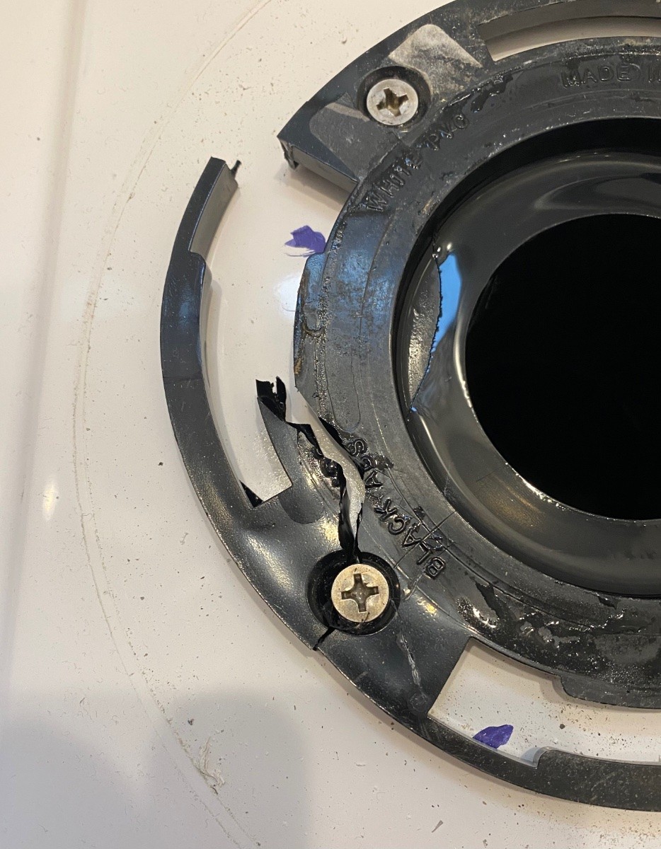 Cracked plastic toilet flange in a travel trailer, highlighting a common cause of black water leaks and odor issues related to the travel trailer toilet seal.