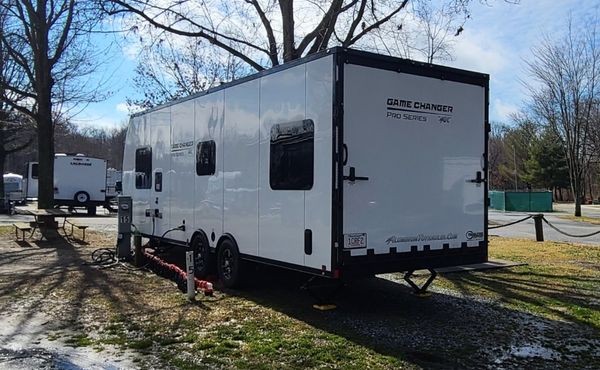 Travel trailer parked very close to hookups to accommodate SolidStep RV steps deployment on a partially paved campsite