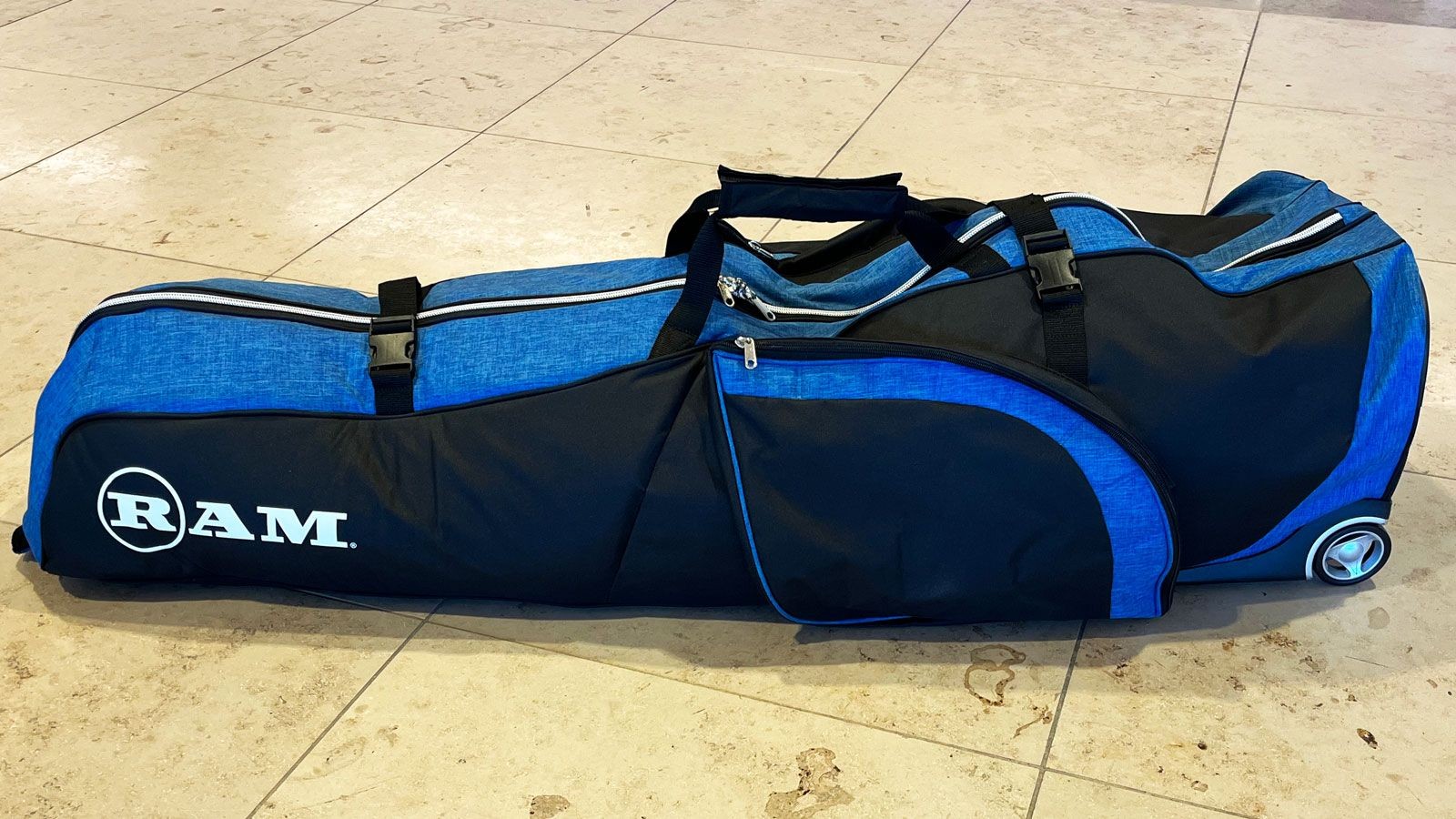 Ram Fx golf travel cover resting on an airport floor, showcasing its affordability and practical design