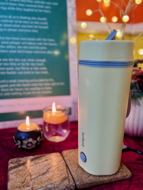 Yellow Balbali portable electric kettle next to two candles on a tea table