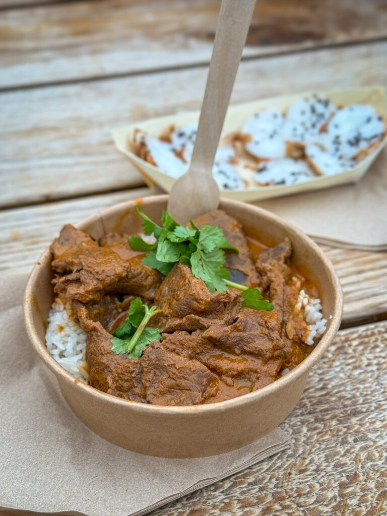 A bowl of beef curry from a food stall at Borough Market, showcasing its rich color and fragrant spices