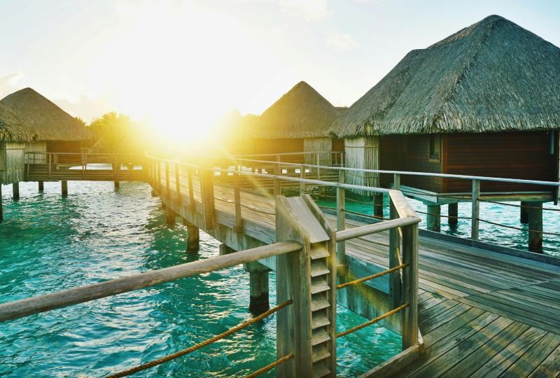 Overwater bungalows in Bora Bora, French Polynesia, a premium travel spot famous for crystal-blue lagoons and lush landscapes.