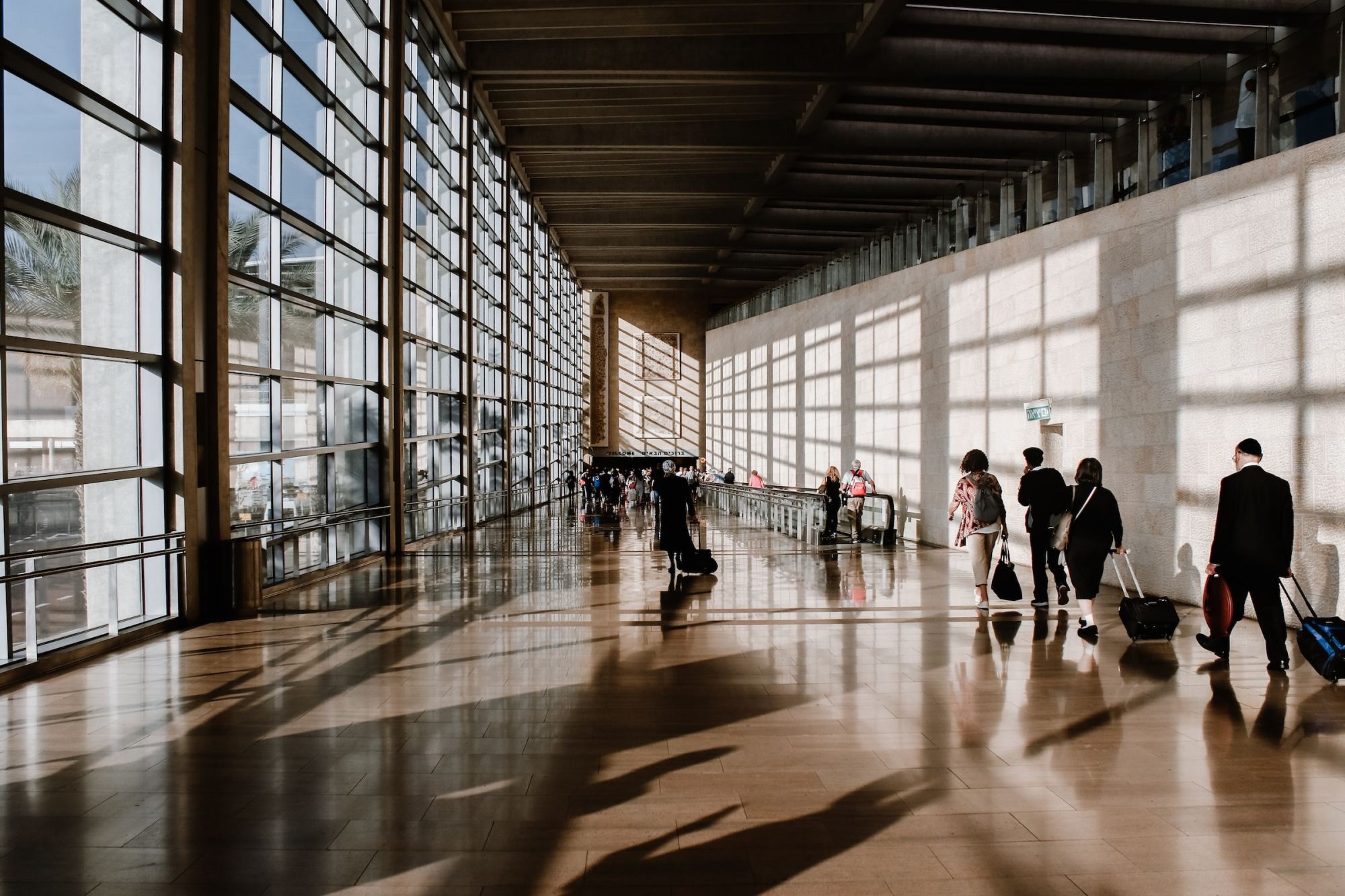 Three business professionals walk through an airport, engaged in conversation, showcasing the dynamic pace of business travel.