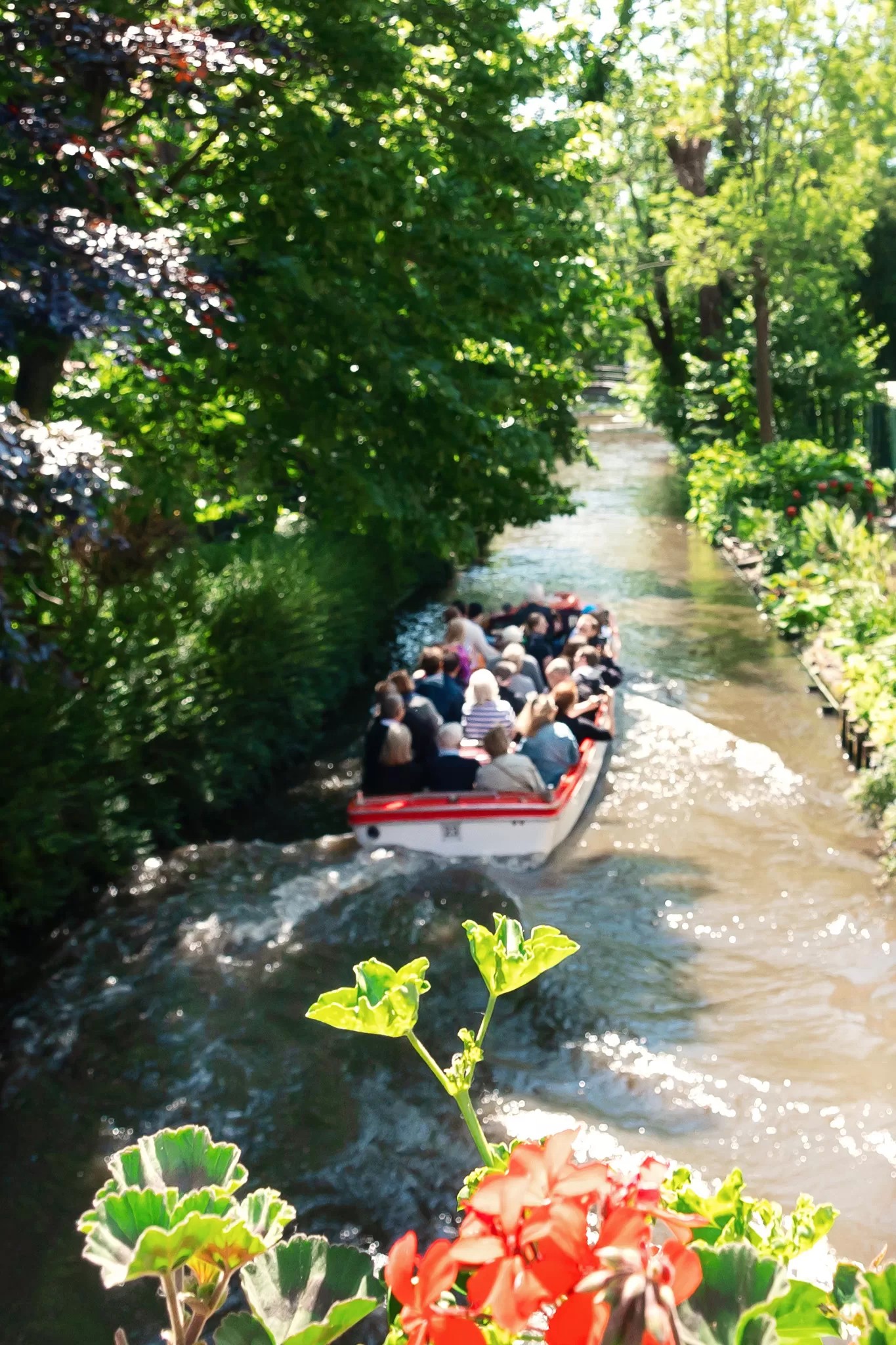 a red and white tour boat full of people in the canal in Bruges, Belgium