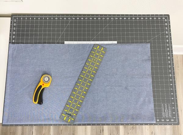 Cutting fabric and towel into 28x20 inch rectangles on a cutting mat.