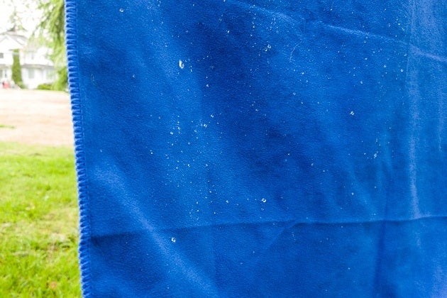 Close-up of water droplets beading on a blue travel towel, demonstrating its water-repellent and quick-drying properties.