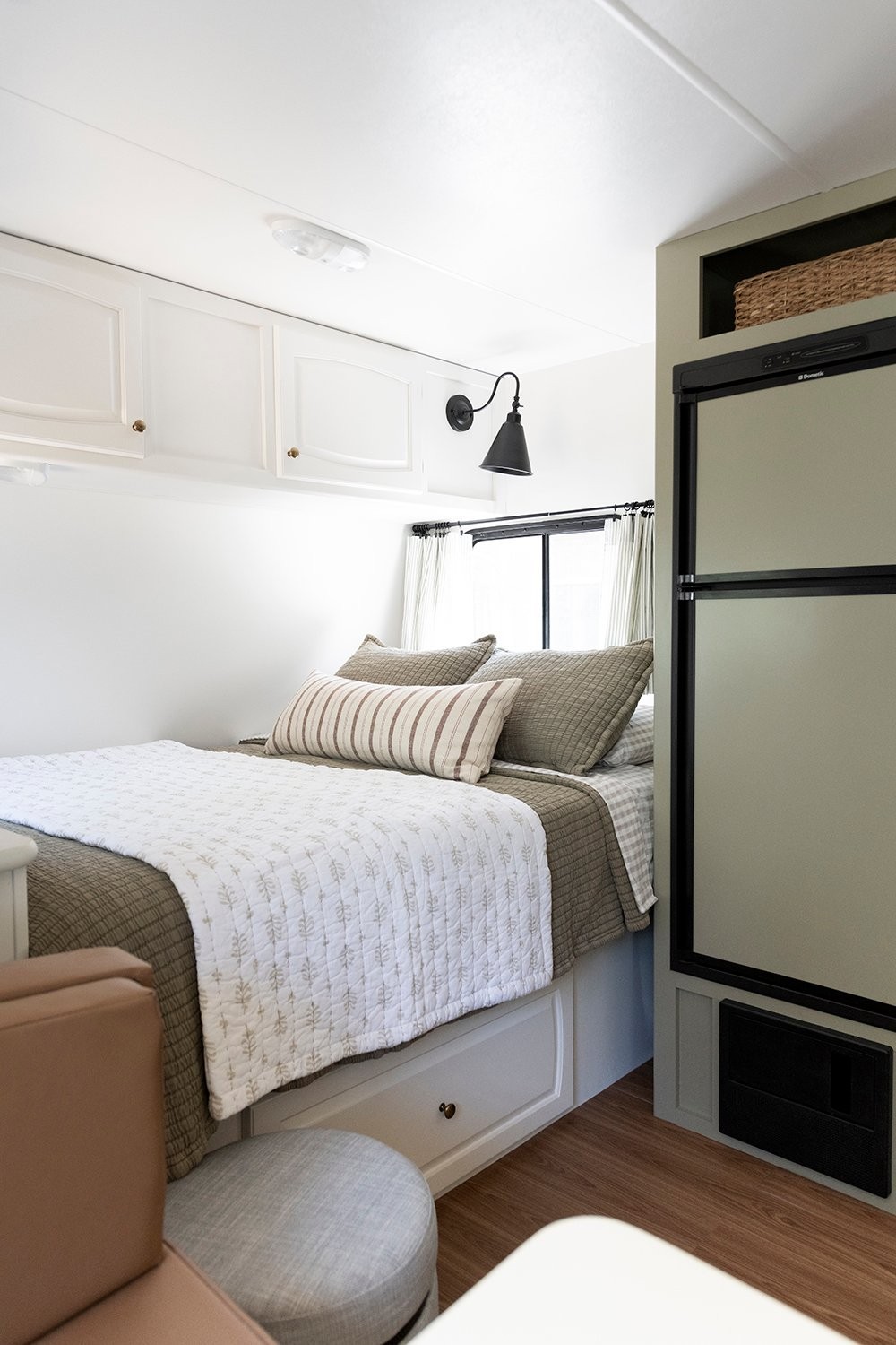 Storage ottoman used as laundry hamper in camper bedroom