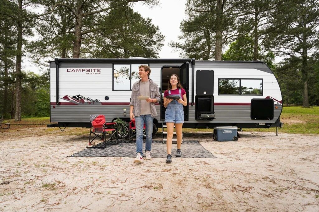 Couple exiting Forest River Campsite Reserve 25MW travel trailer with king bed