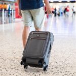 A person walking through an airport with the Travelpro Platinum Elite carry-on bag.