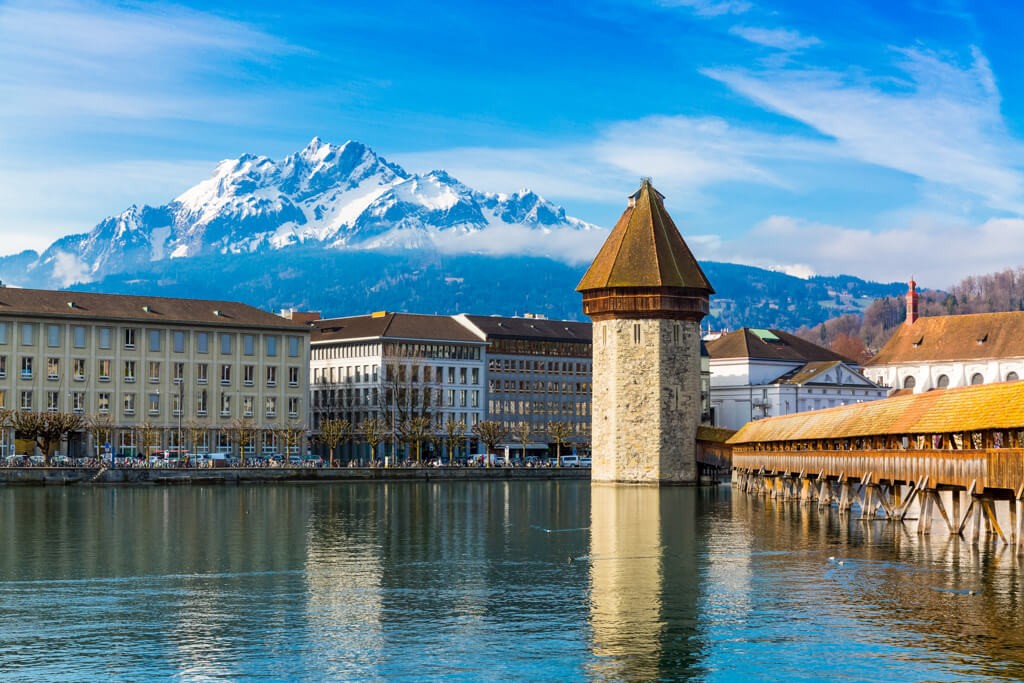 A picturesque view of Lucerne, Switzerland, featuring the iconic Chapel Bridge spanning across the Reuss River in the old town.