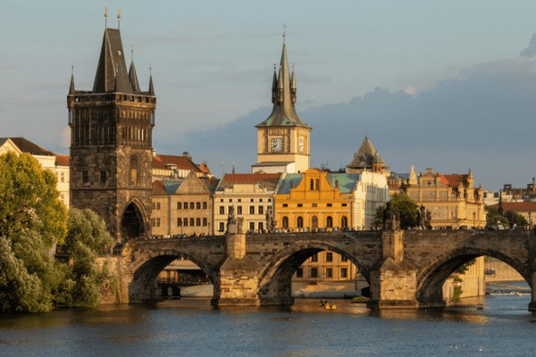 Prague's Charles Bridge and Prague Castle in the background, illuminated at dusk, presenting Prague as a bohemian paradise for budget-conscious travelers in Europe