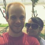 A couple taking a selfie in Chiang Khong, Thailand with Mekong river and greenery in the background.