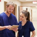 An ER nurse attentively reviews a patient's chart in a busy emergency room setting.