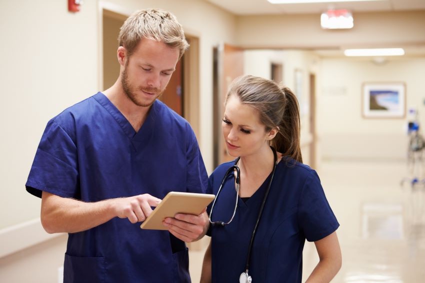 An ER nurse attentively reviews a patient's chart in a busy emergency room setting.