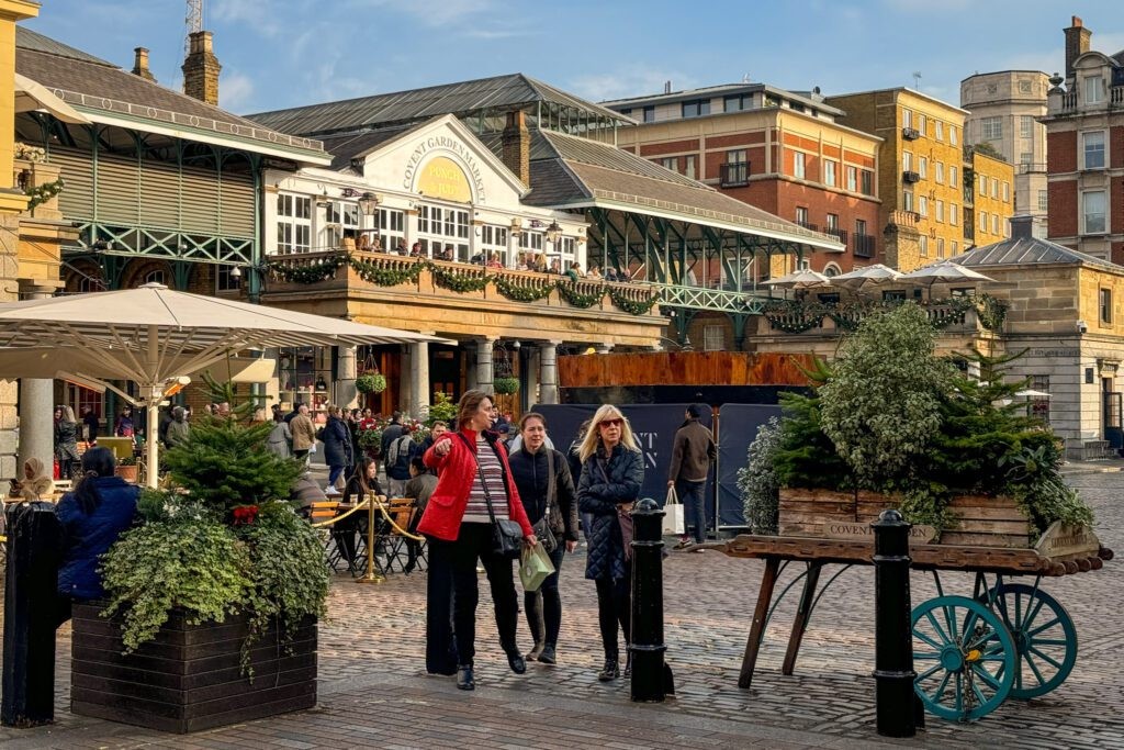 Covent Garden's historic market building, now housing shops and restaurants, with people strolling through the piazza