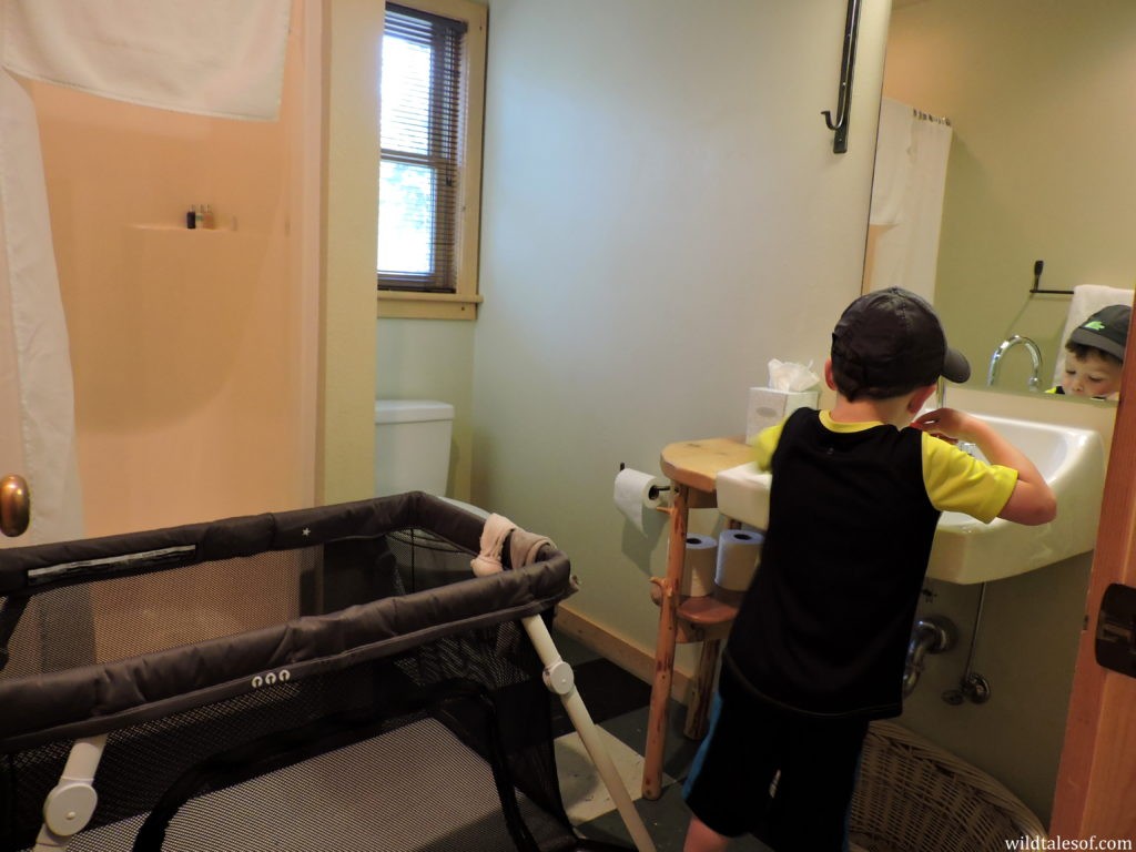 Travel crib setup in a bathroom to create a separate sleeping space for a toddler.