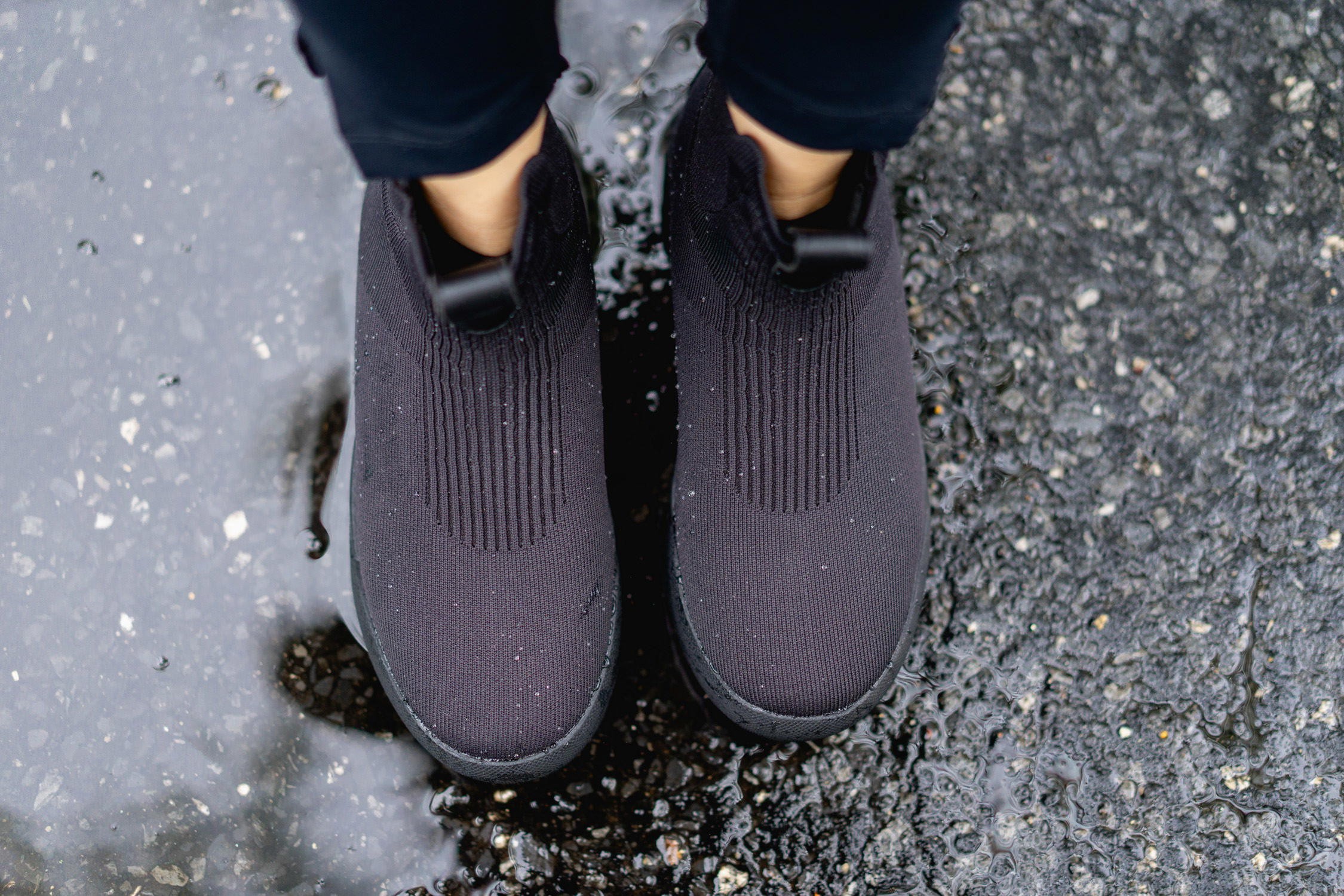 Woman wearing Vessi Weekend Chelsea waterproof travel boots standing on cobblestone street.