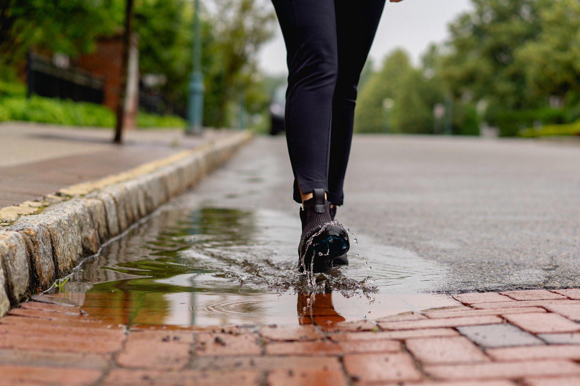 Close-up of Vessi Weekend waterproof sneakers in a puddle, demonstrating water resistance.