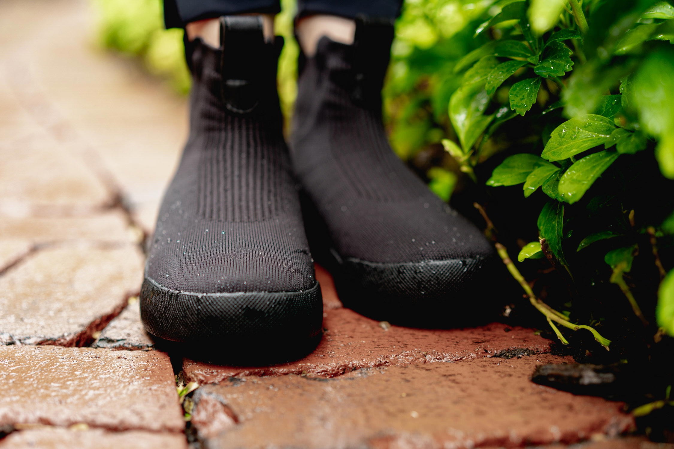 Man wearing Vessi Weekend waterproof travel shoes sitting on a park bench.