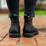 Man wearing white Vessi Weekend waterproof travel shoes standing on a wet street.