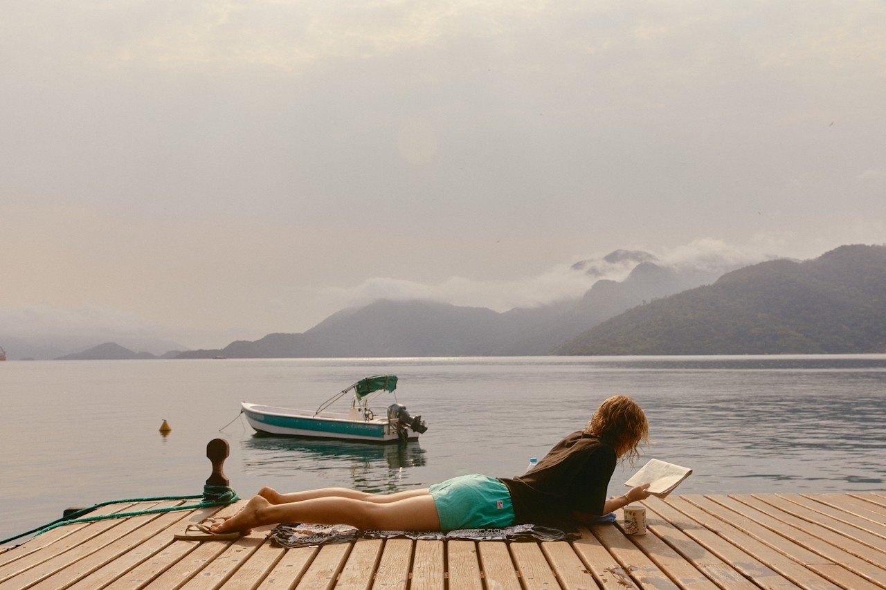 Woman reading a book on a dock by a lake