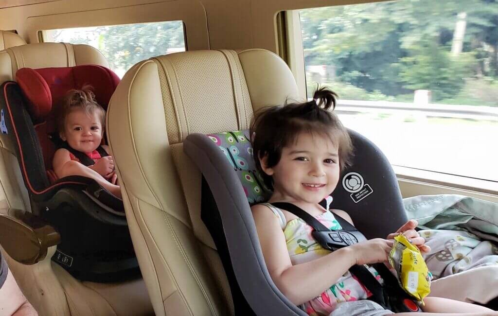 child and baby each in a car seat in large van