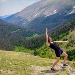 Woman standing in front of snowy mountains, pondering the spelling of traveler or traveller