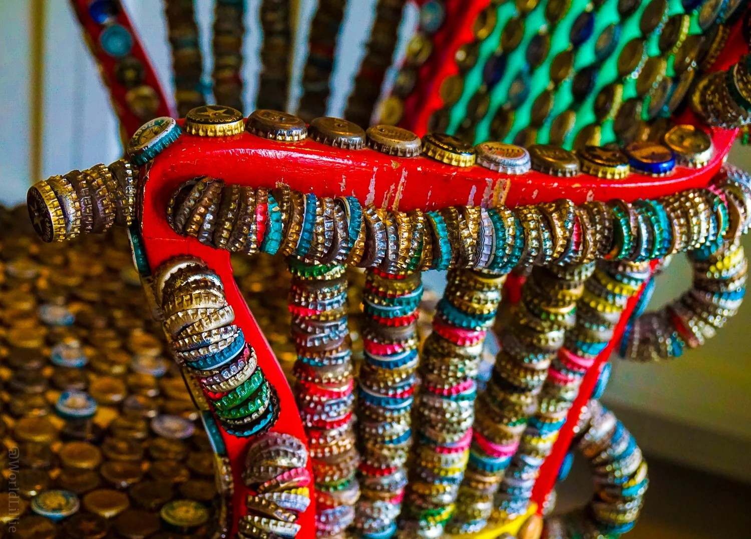 A unique chair made of bottle caps, prompting the thought of traveling to see unusual sights