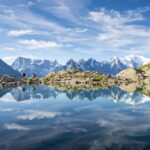 Hikers reflected in Lac Blanc on the Tour du Mont Blanc trekking route in the French Alps near Chamonix