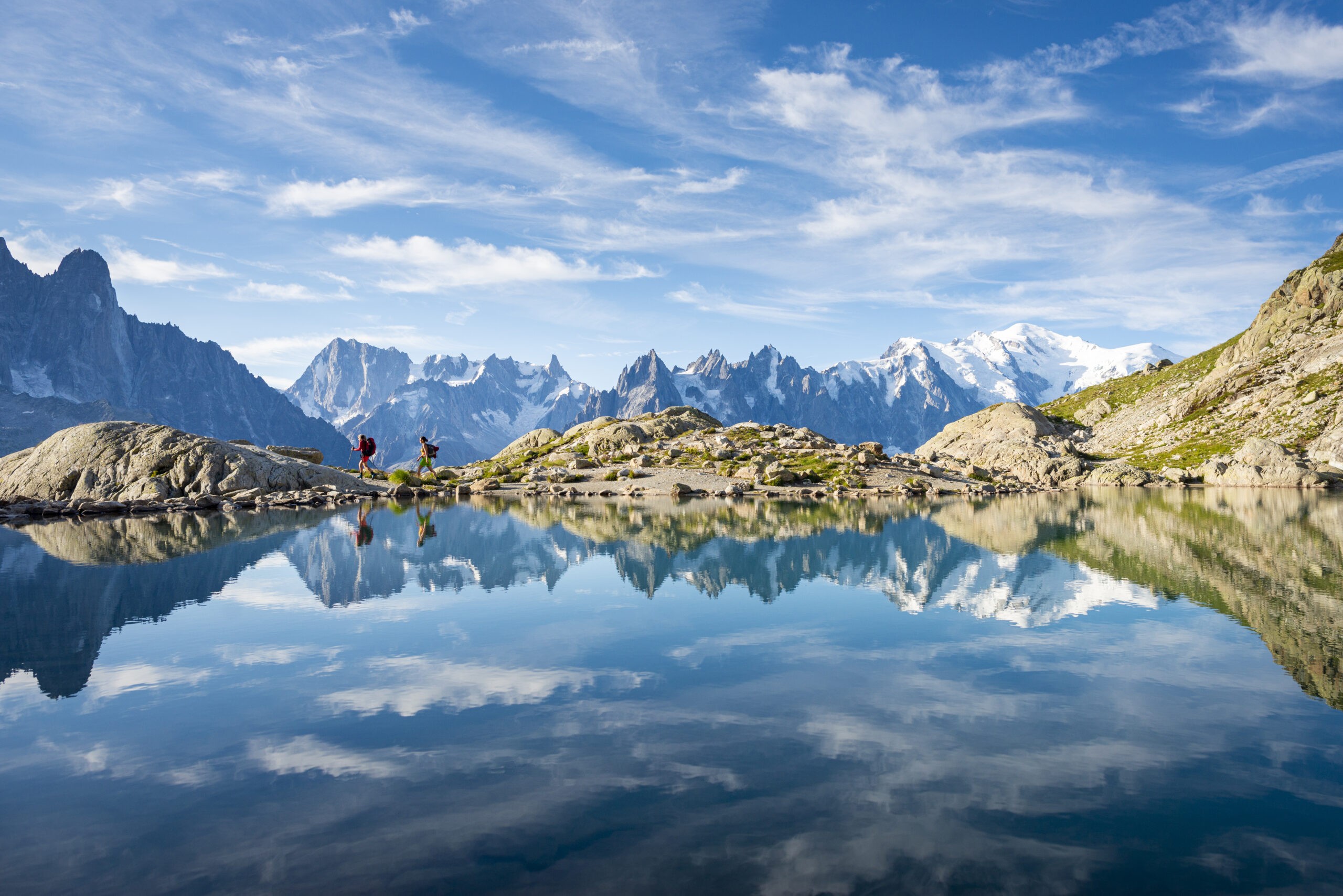 Hikers reflected in Lac Blanc on the Tour du Mont Blanc trekking route in the French Alps near Chamonix