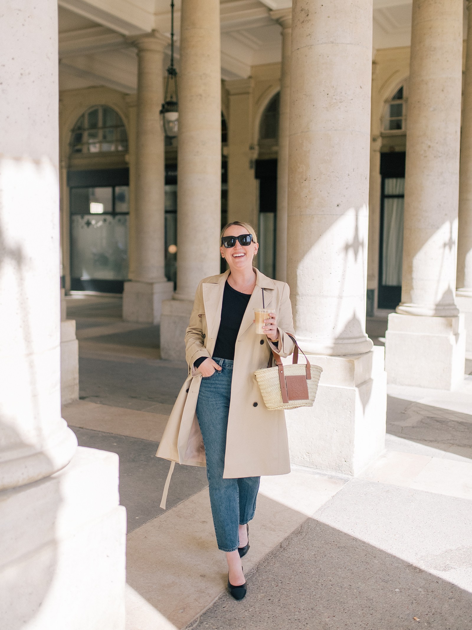 Woman in trench coat and jeans, showcasing Europe travel trench coat outfit