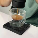 Close-up of Outin Nano portable espresso maker extracting a shot of espresso