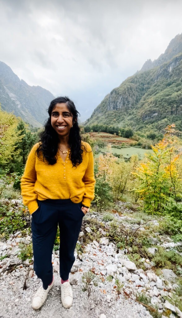 A woman wearing navy blue travel pants stands on a trail, showcasing the best travel pants for women for comfort and style.