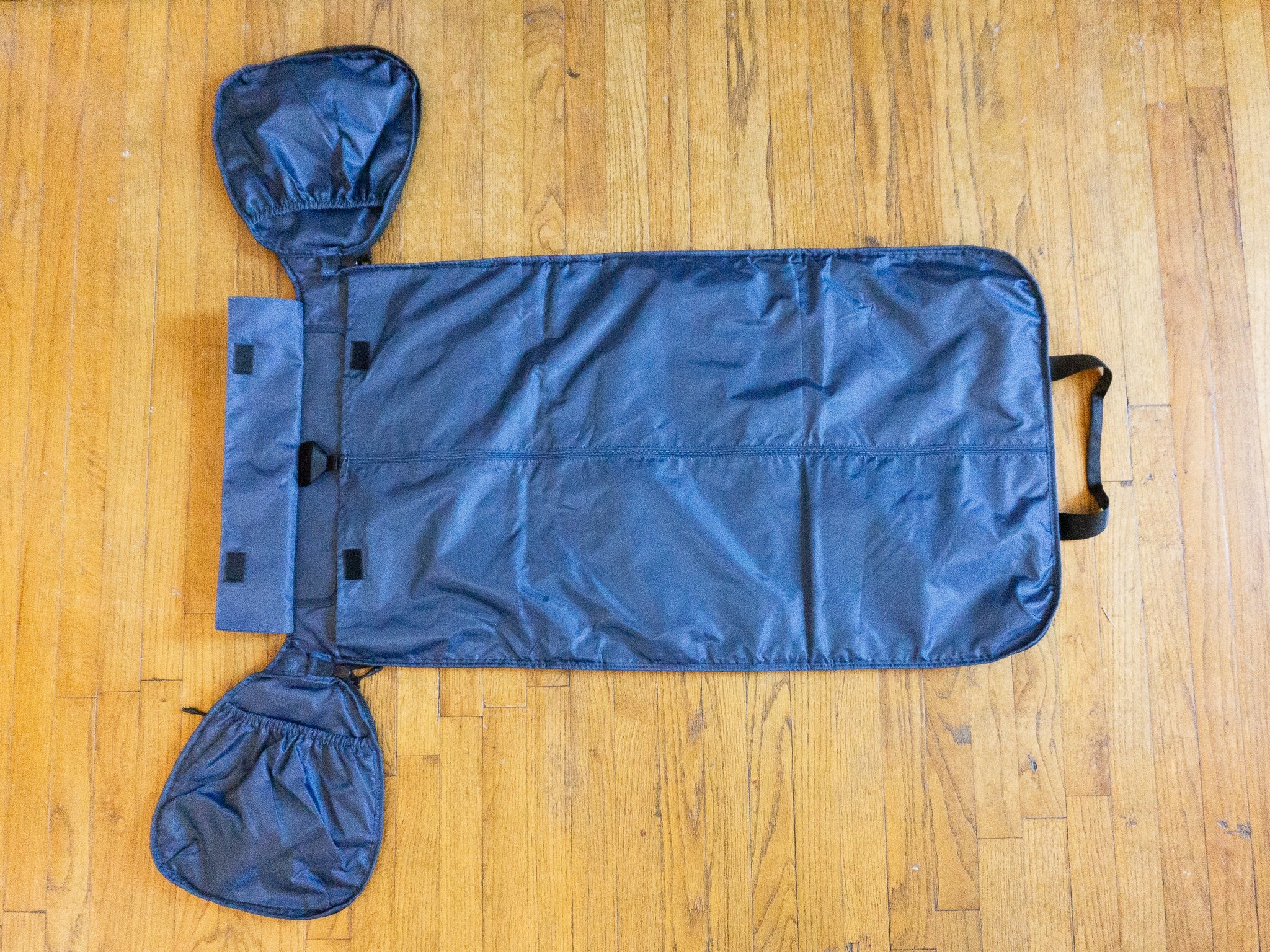 The Halfday Duffel bag fully unzipped and laid flat on a wooden floor, revealing its garment bag and duffel compartments.