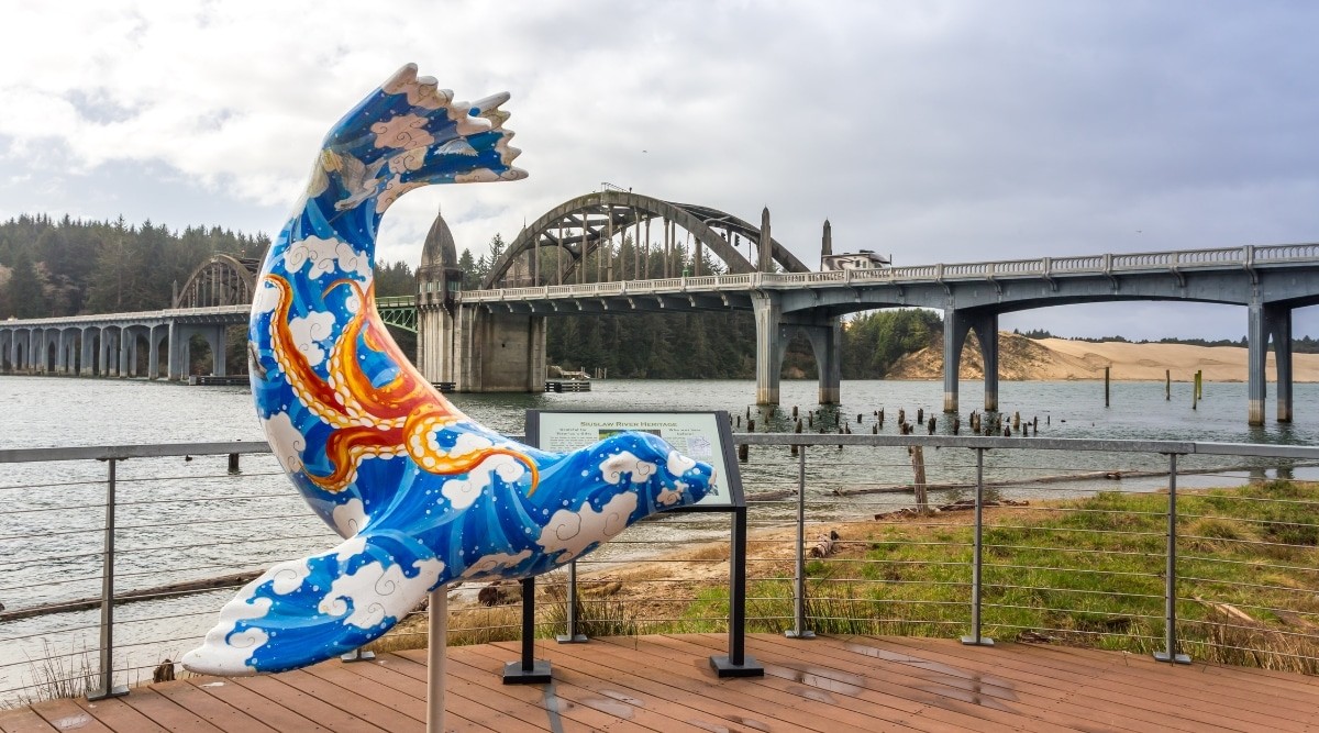 Bridge in Florence, Oregon, featuring a blue seal statue in the foreground and cloudy skies.