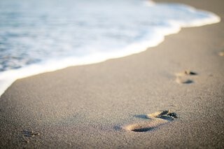 Footprints in the sand, symbolizing a wayfarer's journey along the shore