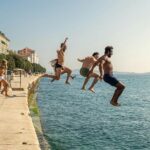 Group of courageous people jumping into harbour sea of Zadar, Croatia