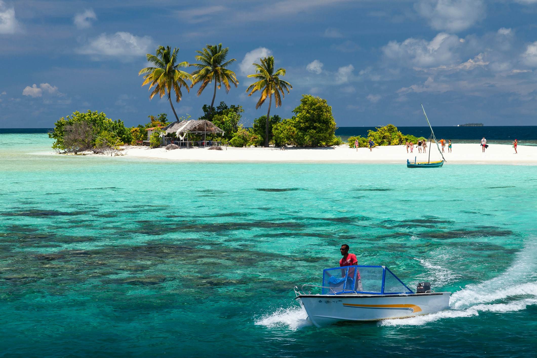 Maldives islands, with turquoise waters and a speedboat departing from a small sandy island, offer paradise on Earth