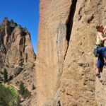 Rock climbing adventure at Smith Rock State Park, a popular summer activity in Oregon. Plan the best time to travel to Oregon for outdoor sports and secure campsites in advance.