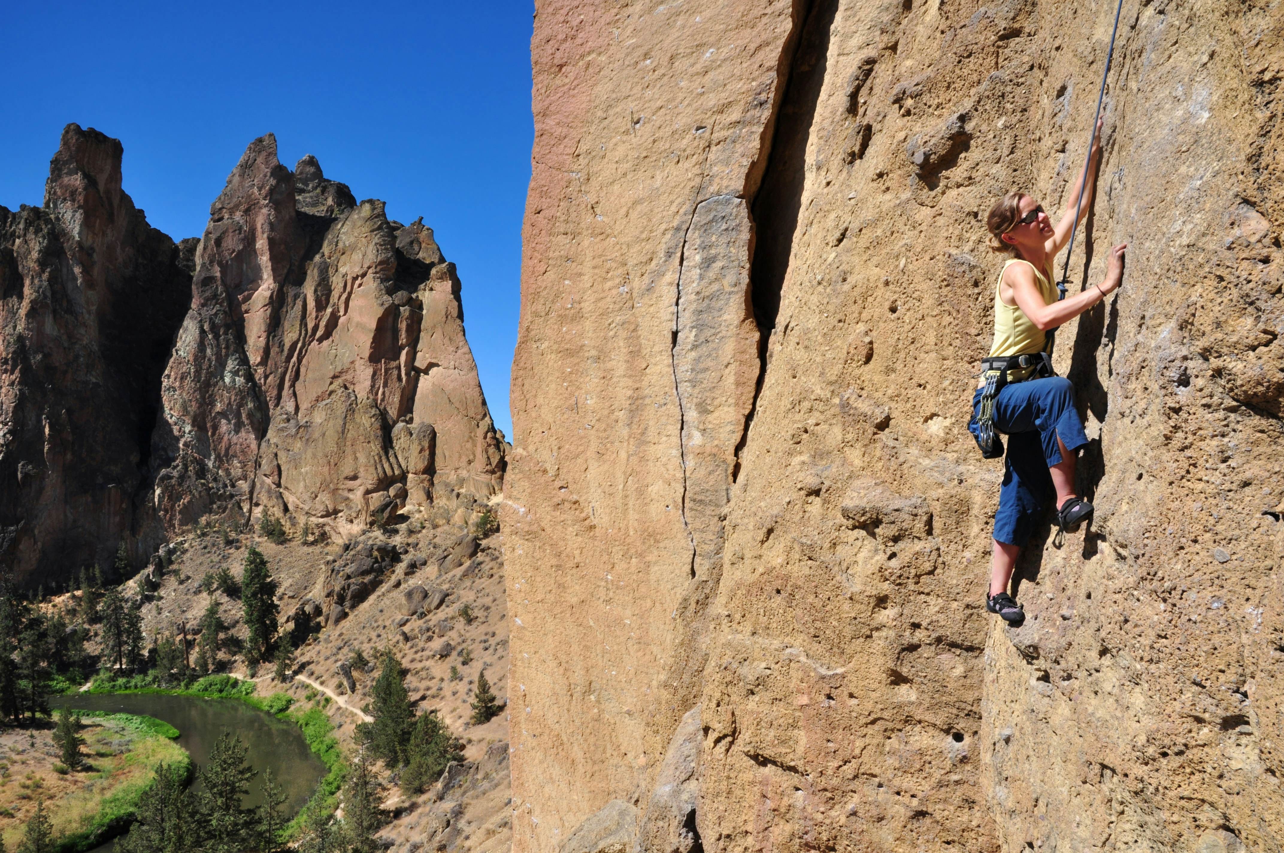 Rock climbing adventure at Smith Rock State Park, a popular summer activity in Oregon. Plan the best time to travel to Oregon for outdoor sports and secure campsites in advance.