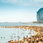 Visitors enjoying the beach in Barcelona during the peak summer months.