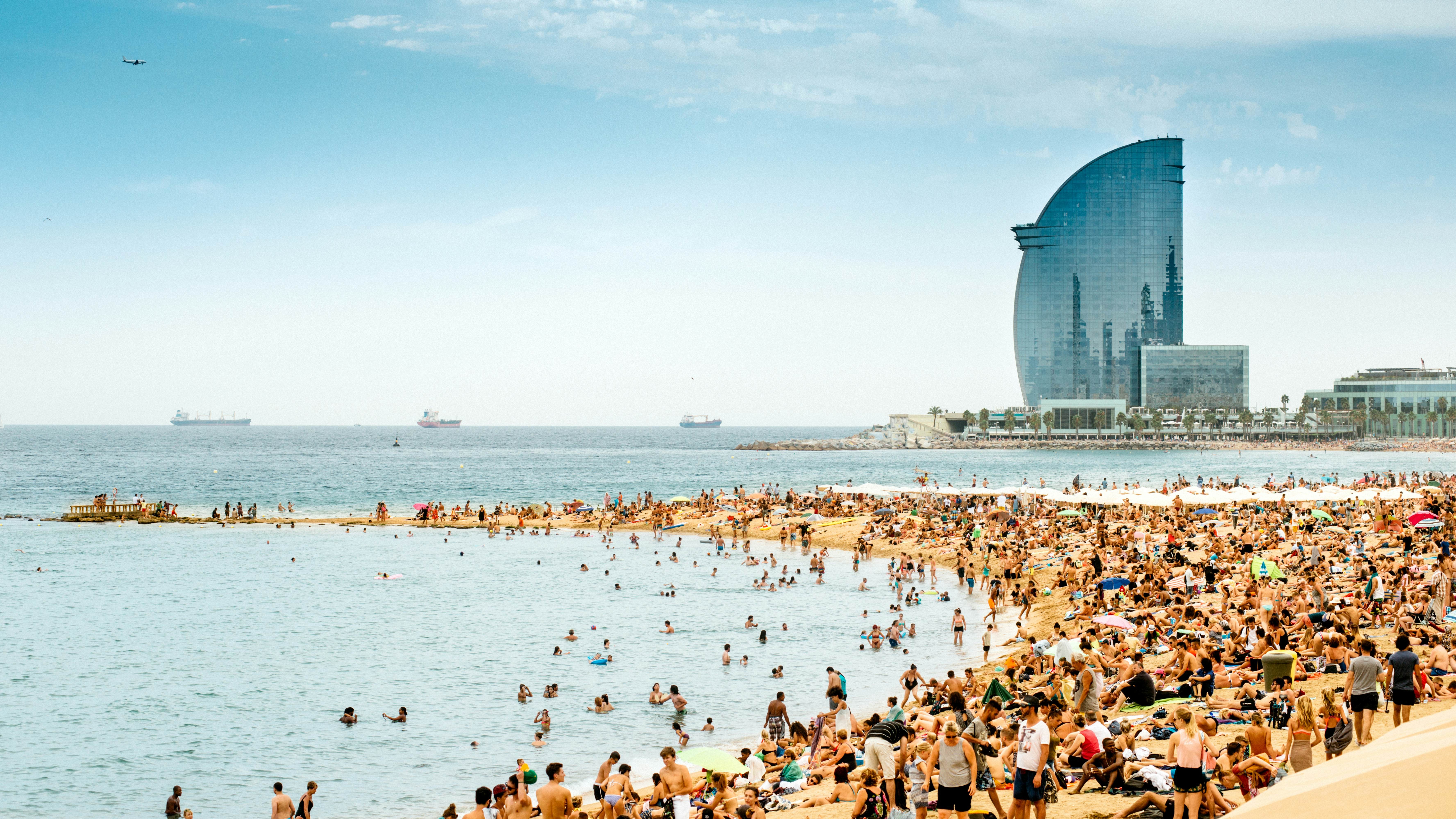 Visitors enjoying the beach in Barcelona during the peak summer months.